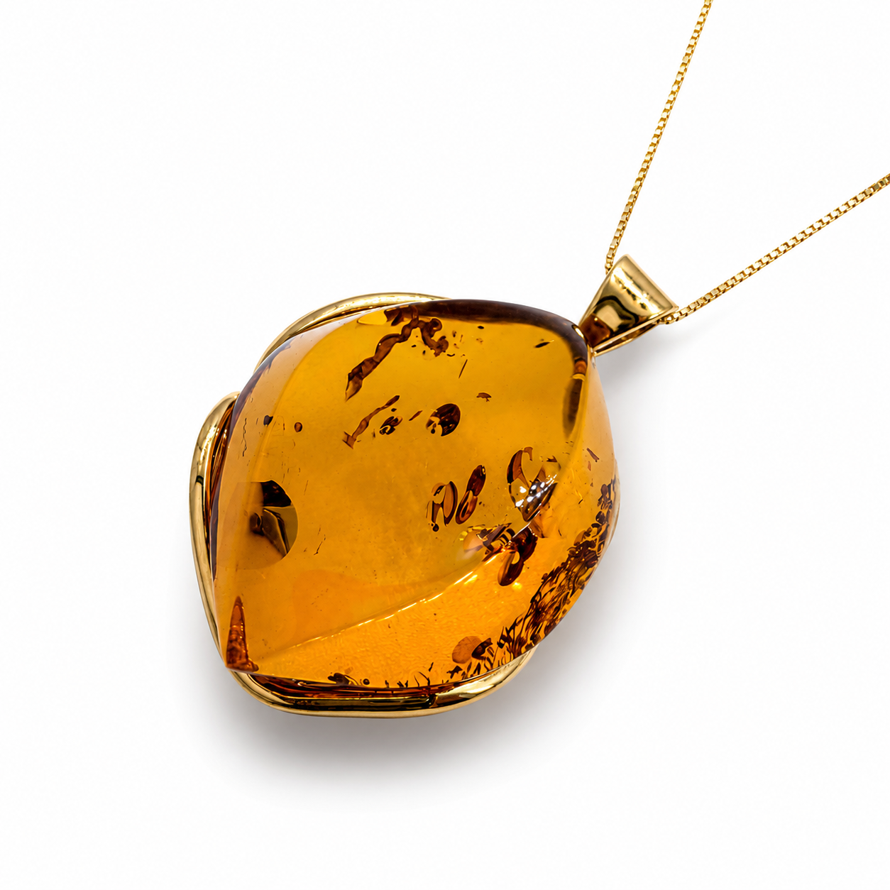An irregularly shaped amber pendant necklace with a gold-toned bezel setting and matching chain, shown on a clean white background.