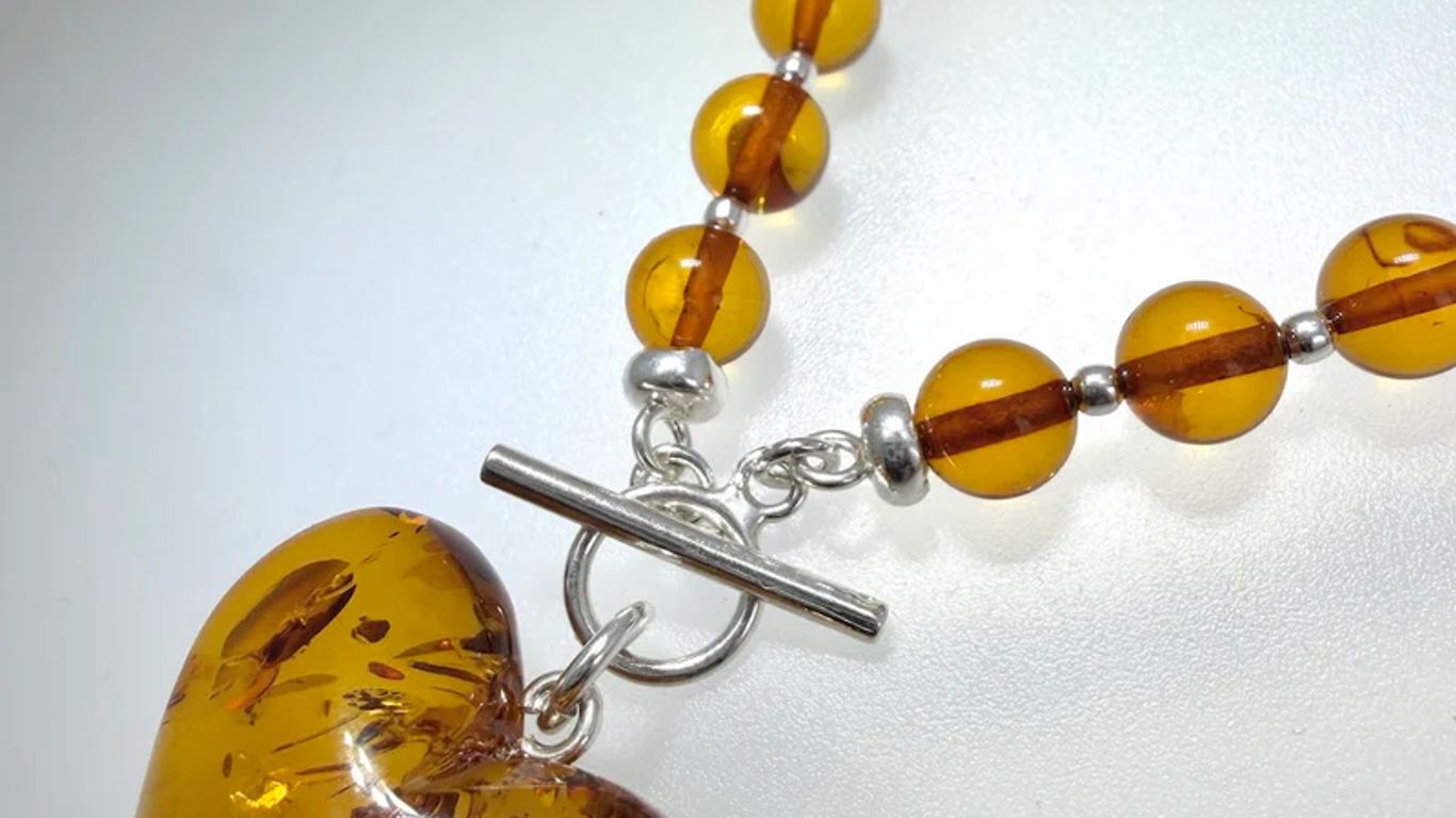 A heart-shaped amber pendant necklace with amber beads and silver clasp.
