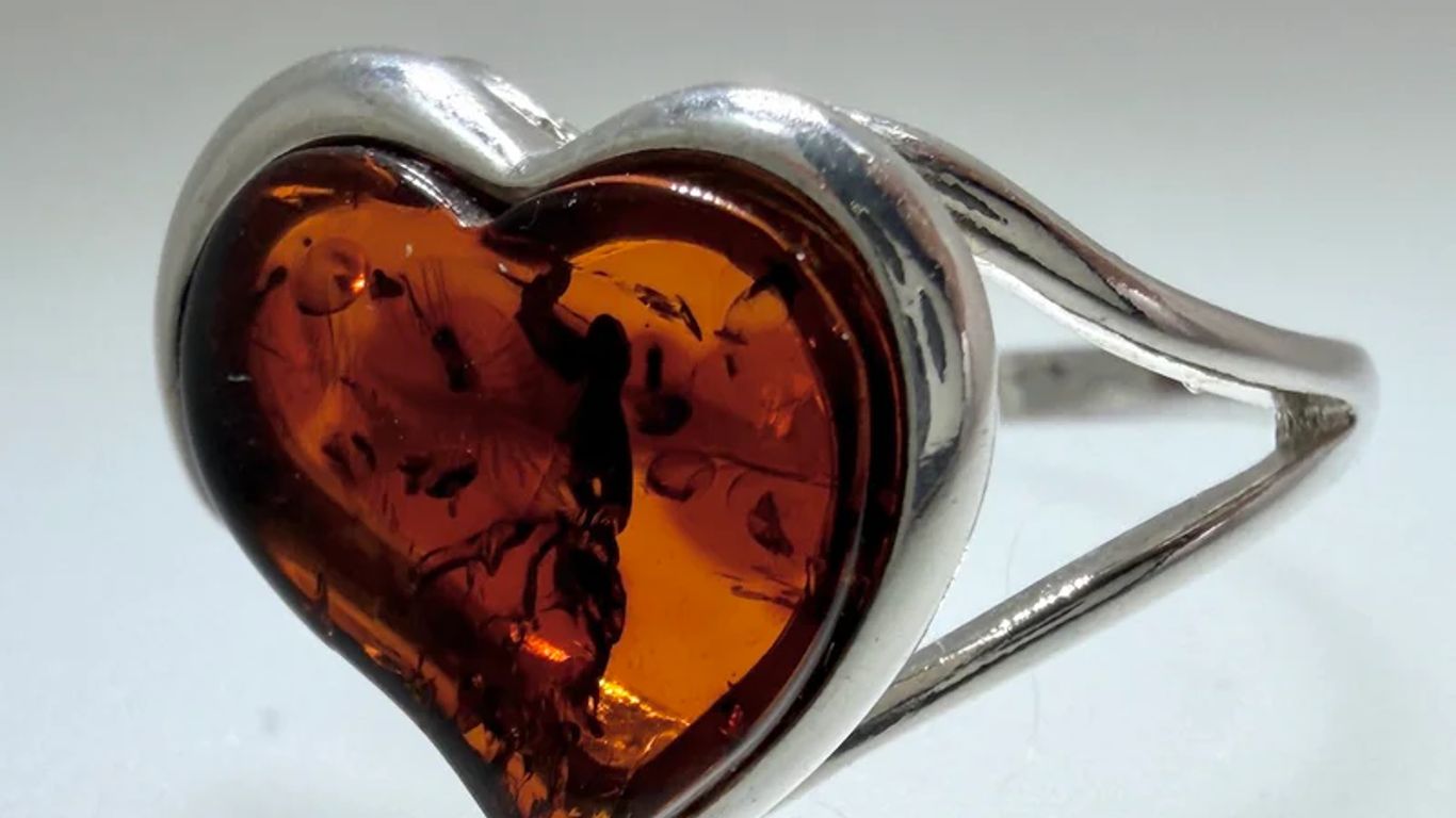A silver ring with a heart-shaped amber stone.