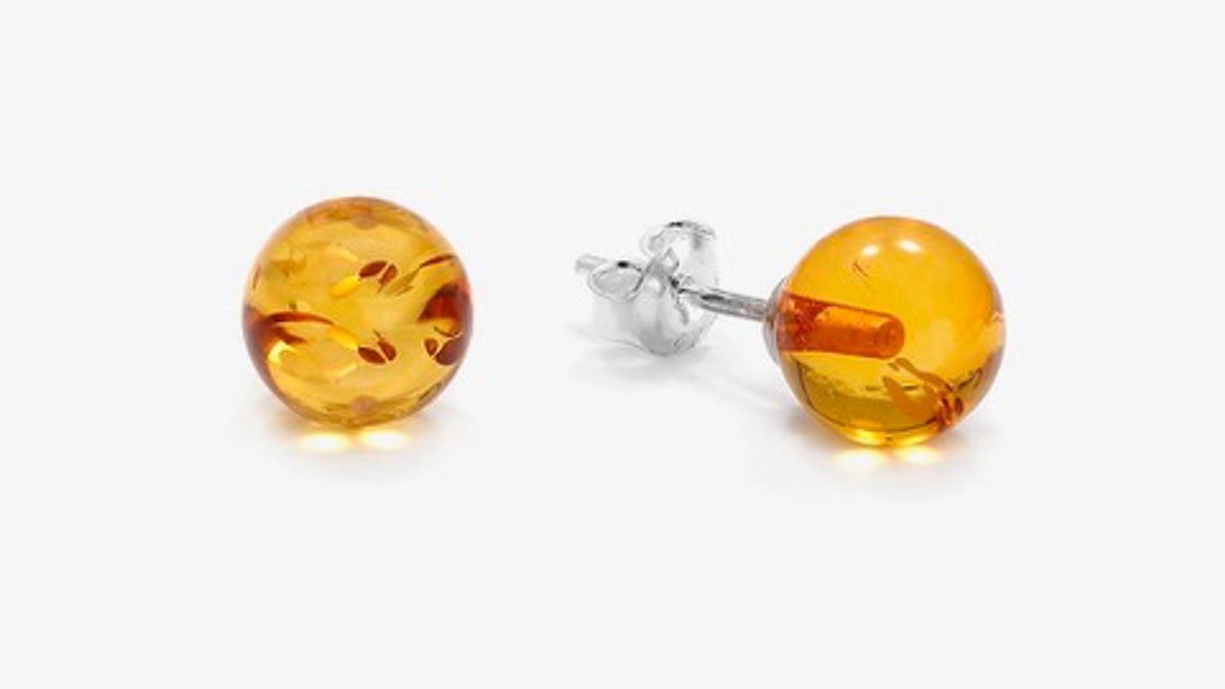 A pair of round, amber stud earrings with silver posts.
